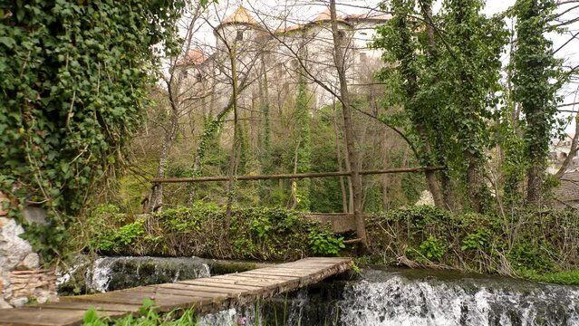 Static low-angle shot of a wooden bridge across a small waterfall on the Krka river