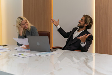 Young businessman and businesswoman work together to finish a project report. Two employees discussing about works.