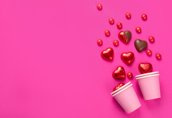 Wrapped and unwrapped heart shape chocolate candies in red foil on pink background