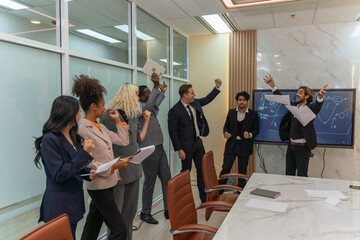 Group of businessmen and businesswomen cheers to celebrate their latest successful deal in a office meeting room. A team of sales person celebrate new high sales report.