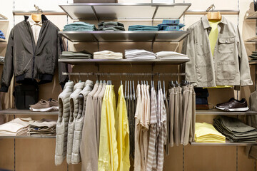 Men's clothing on hangers in a boutique grouped by color. Jackets, trousers and shoes. Fashion & Style.