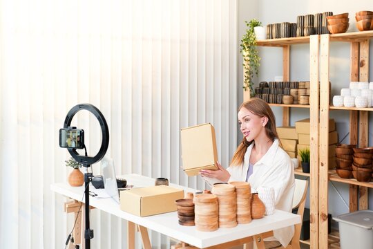Attractive Caucasian influencer girl review and record live video for share on social media with handmade product stock background