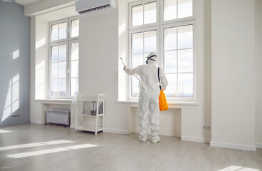 Professional pest control inside the house. Exterminator wearing protective suit, mask and gas...
