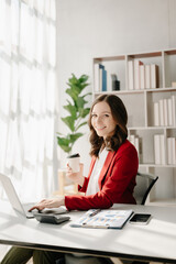 Confident Asian woman with a smile standing holding notepad and tablet at the modern office..