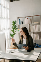 Fototapeta na wymiar Confident business expert attractive smiling young woman typing laptop ang holding digital tablet on desk in creative home office.