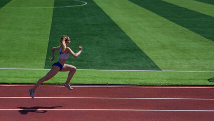 Obraz premium Young caucasian woman is engaged in jogging at the stadium outdoors.