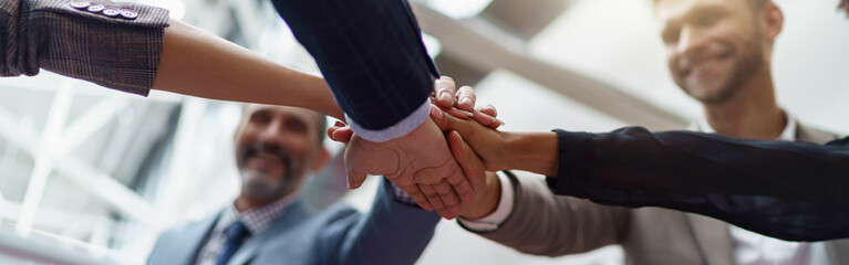 Happy group of business coworkers stacked hands together as concept of corporate unity