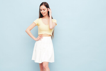 Image portrait of optimistic woman in yellow  t-shirt and white skirt. Carefree stylish model with long hair. Smiling female posing in studio. Isolated. Looks delightful and cute. Slim