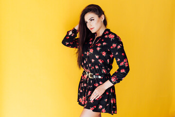 female brunette on a yellow background posing