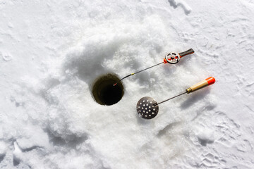 Fototapeta na wymiar Winter fishing. Fishing rod next to the hole. Waiting for a trophy in the cold season. Close-up