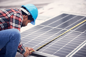 Technician, measuring tape and solar panel on rooftop for check, planning or renewable energy project. Black man, photovoltaic system and roof installation with focus, sustainable building or service © Jordan C/peopleimages.com