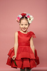 little girl in red dress with flowers in hair dress happy closeup portrait on pink background