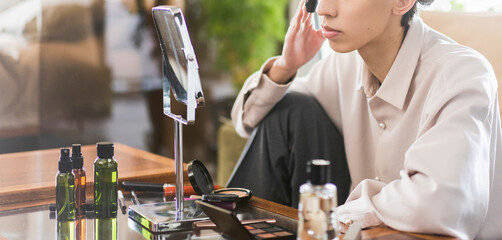 自宅リビングでメイクをしている若いアジア人男性/メンズビューティー