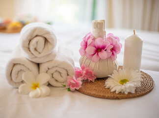 Fototapeta na wymiar The white linens and scented candle on the bed create a peaceful and relaxing spa atmosphere.