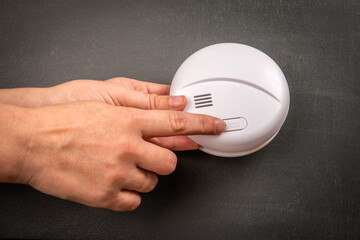 Fototapeta na wymiar Smoke alarm detector in woman's hand, black chalkboard background