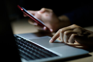 Business man using smart phone, tablet in Dark room. hand holding smart phone , tablet. lap top in front of him.	
