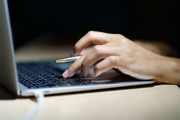 Close up of a man's hands on keyboard of lap top in the dark room, people working at home, modern white notebook. Internet, work, technology concept.