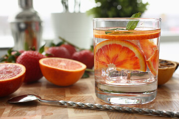Red orange punch with green mint and ice in a glass. Making homemade refreshing summer cocktail