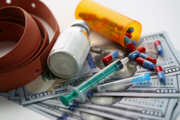 Medical syringe with white cocaine powder and medical pills on dollar bills. Income from the drug trade concept