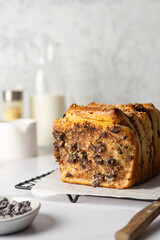 Sweet yeast pull-apart bread with cream cheese, chocolate, prunes and nuts. Homemade baking with ingredients on concrete background.