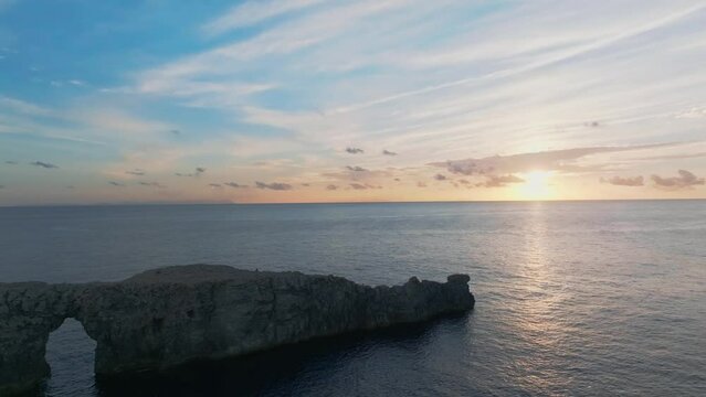 Drone flying around the cliffs of Port den Gil at sunset along the spectacular coastline of Menorca.