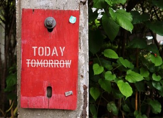 Wood sign board with handwritten stick note TOMORROW, crossed off to TODAY, concept of to take action now, no more excuses or procrastination, Make it happen today, not tomorrow