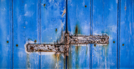 Rusty hinge on Old Blue wooden door in Spain