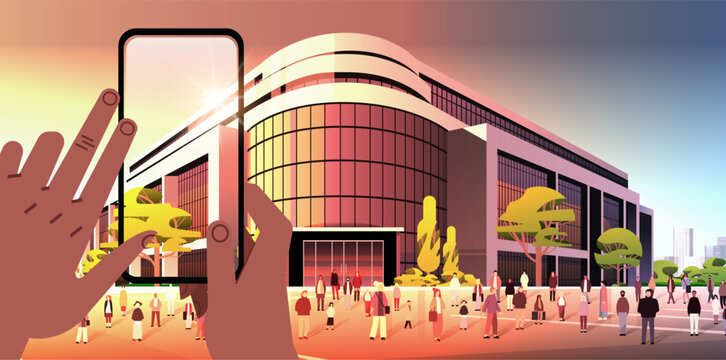 human hands taking photo of modern office building commercial business center with large panoramic windows