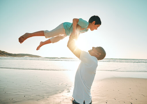 Father, playing and flying son on the beach at sunset together for bonding during summer vacation or holiday. Family, ocean or kids with a man and a happy boy child on the seaside coast by the ocean