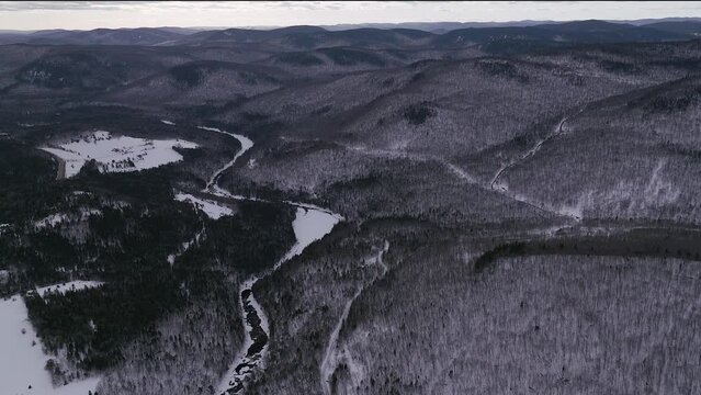 Aerial scenic drone forward motion Canadian  wilderness mid winter near north Quebec Stoneham Ski Resort of frozen over Sautaurski River upstream National Park Jacques Cartier