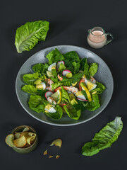 A bowl of salad with shrimps and salmon with a bowl of potato chips, lemon and  salad dressing