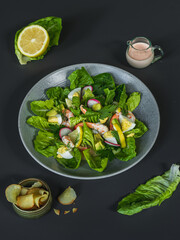 A bowl of salad with shrimps and salmon with a bowl of potato chips, lemon and  salad dressing