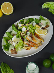 A bowl of salad with shrimps and salmon with a bowl of potato chips, lemon and  salad dressing