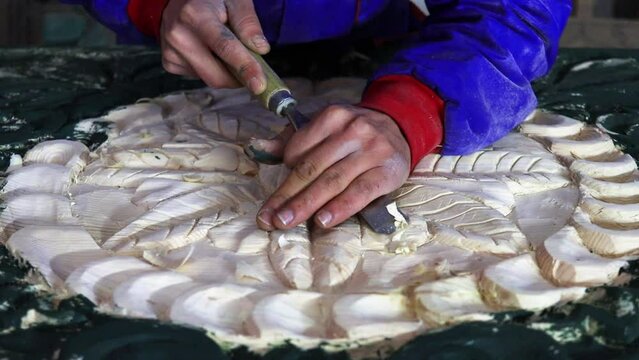 Close Up of Man Hands carving on wooden furniture. Carpenter using tool making Artistic Wood Carving. Producing an Ornament on Wood with Chisel and Hammer on a Panel of Wood . High quality 4k footage