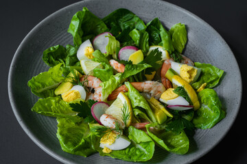 A plate of salad with shrimp, radishes, and egg.