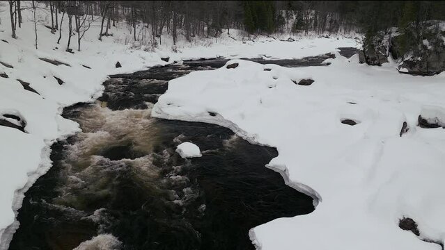 Aerial scenic drone backward motion Canadian  wilderness mid winter near north Quebec Stoneham Ski Resort of frozen over Sautaurski River downstream