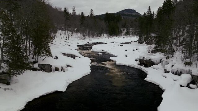 Aerial scenic drone backward motion Canadian  wilderness mid winter near north Quebec Stoneham Ski Resort of frozen over Sautaurski River down stream
