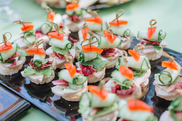 finger food. slices of cheese and tomatoes on a skewer. Italian appetizer skewers with cheese, cherry tomatoes and olives on wooden sticks on a black board, catering, banquet