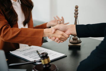 Woman lawyer hand and women client shaking hand collaborate on working agreements with contract documents at the modern office..