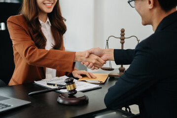 Woman lawyer hand and women client shaking hand collaborate on working agreements with contract documents at the modern office..