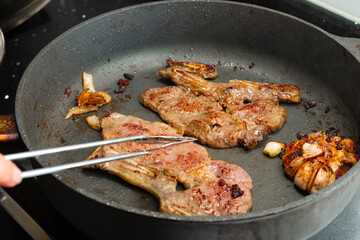 frying two pieces steaks on a pan at home