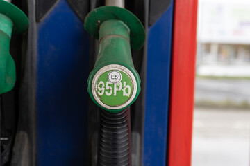 Fototapeta premium Unleaded 95 gasoline. Fuel nozzle with hose, attached to the gas station column. Pb 98 E5 pump stand or dispenser machine at self-service petrol filling station.