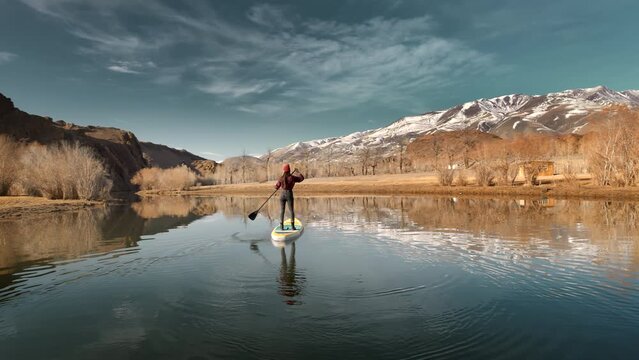 Slim sporty girl is walking on stand up paddle sup board at calm mountain in mountains river