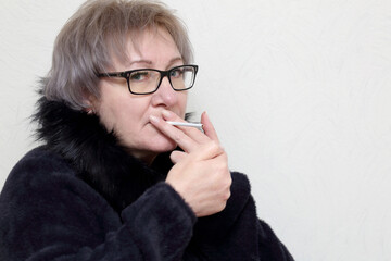 young woman with glasses lights a cigarette - 594920125
