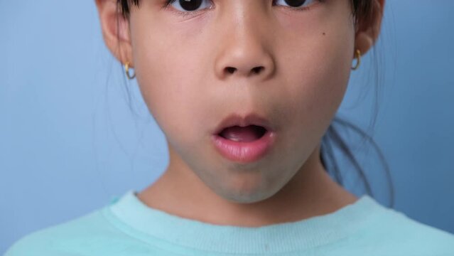 Cute little girl chewing gum on blue background. Portrait of a cute little girl enjoying eating chewing gum.
