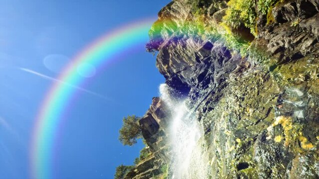 waterfall in mountain ridge woods with the bright rainbow - loop video