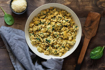 Scrambled eggs with spinach in a white pan
