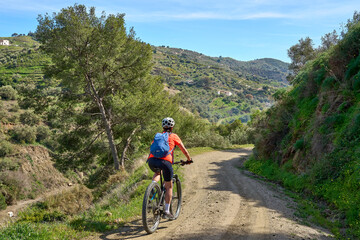 nice senior woman cycling with her electric mountain bike in the Sierra de Tejada near Nerja, Andalusia, Spain - obrazy, fototapety, plakaty