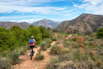 Obraz premium nice senior woman cycling with her electric mountain bike in the Sierra de Tejada near Nerja, Andalusia, Spain