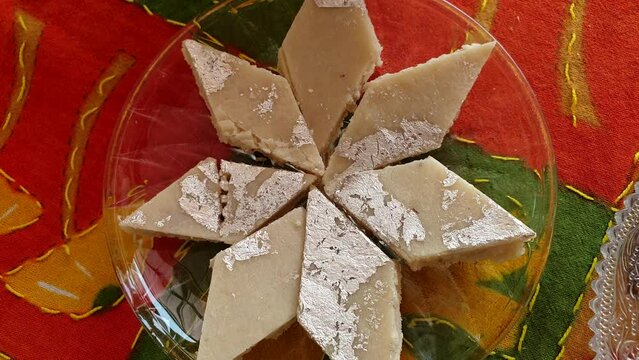 Hand picking burfi barfi Indian sweet milk and cashew nut diamond cut bar with silver dairy milky India food